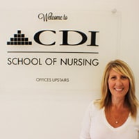 CDI Student Smiling in front of School Sign