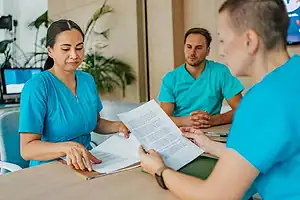 Nursing students discussing paperwork in clinical training setting