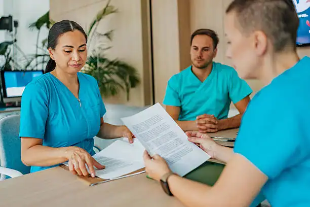 Nursing students discussing paperwork in clinical training setting