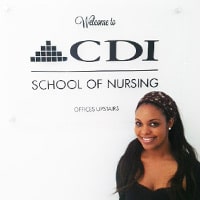 CDI Student Smiling in front of School Sign