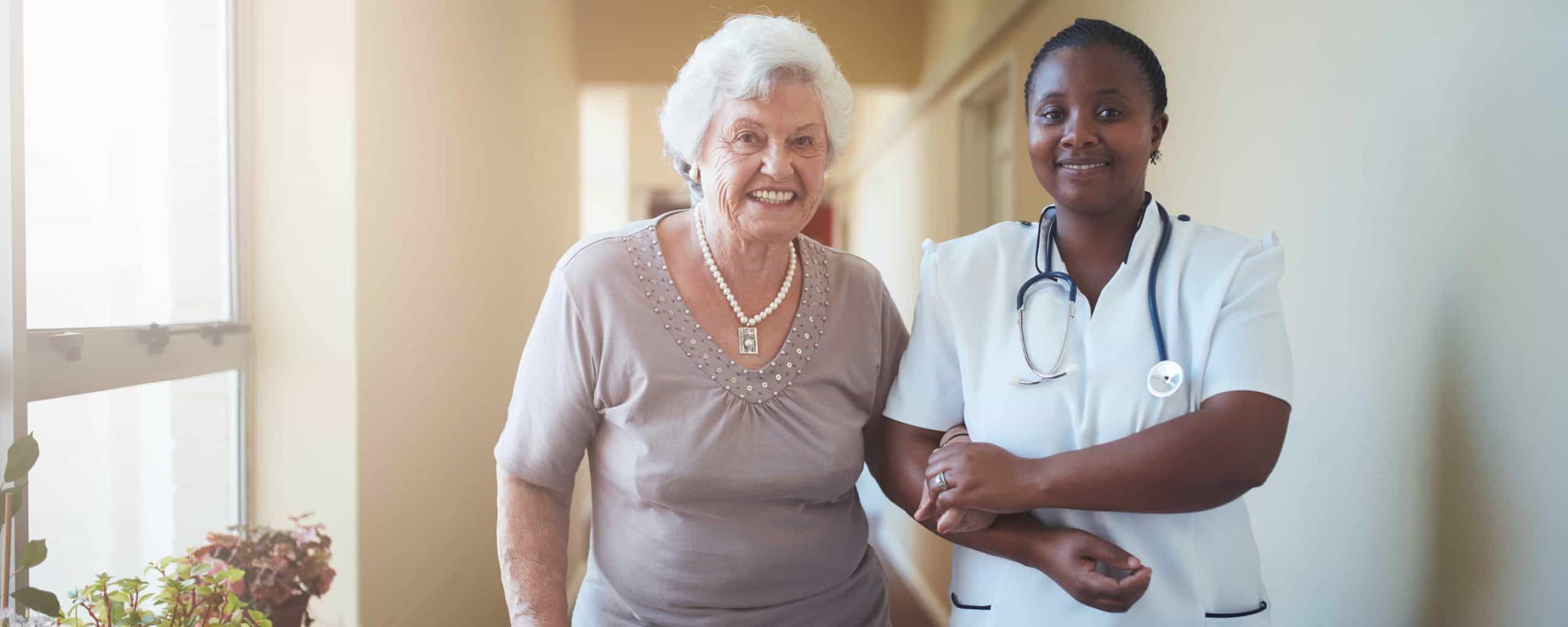 Nurse and patient walking down a hall holding arms